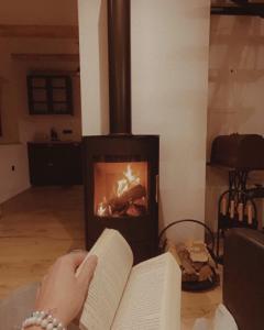 a person reading a book in front of a fireplace at Riverside House Krka in Zagradec