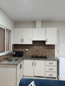 a kitchen with white cabinets and a sink at Luxe 1 Bedroom Apartment in Doha emporium B-17, Margalla views in Islamabad