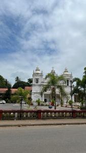 a large white building with trees in front of it at Cozy Corner - Tropical 2BHK pool pad in Varca