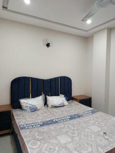 a bed with a blue headboard in a room at Luxe 1 Bedroom Apartment in Doha emporium B-17, Margalla views in Islamabad