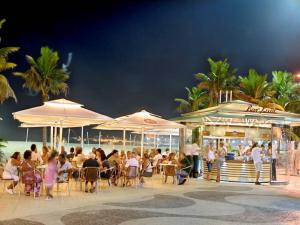 un groupe de personnes assis à des tables sous des parasols sur la plage dans l'établissement Apartamento Atlantica Rio, à Rio de Janeiro