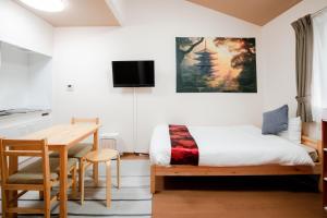 een slaapkamer met een bed, een bureau en een tafel bij Noir Toji Inn in Kyoto