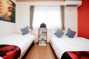 een slaapkamer met twee bedden en een raam bij Noir Toji Inn in Kyoto