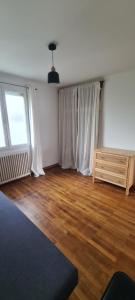 a living room with white curtains and a wooden floor at Maison proche centre ville Nantes in Saint-Herblain