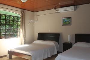a bedroom with two beds and a window at Hotel Santa Maria Inn in Alajuela City