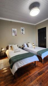 two beds in a room with wooden floors at Ikaya Accommodation PSJ in Port St. Johns +58 photos