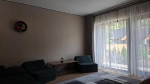 un salon avec un canapé, des chaises et une fenêtre dans l'établissement Respiro Villas, à Tîrgu Neamţ