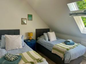 two beds in a room with two windows at Otters Halt & Mouse Hole - Sleeps 12, Pet Friendly in Sparham