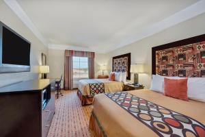 a hotel room with two beds and a flat screen tv at Super 8 by Wyndham Hidalgo at La Plaza Mall & Mcallen Airport in Hidalgo