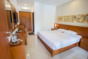 a hotel room with a bed and a television at Sinar Bali Hotel in Legian