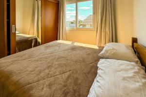 Un dormitorio con una cama grande con ventana. en Casa no Centro de Gramado, en Gramado