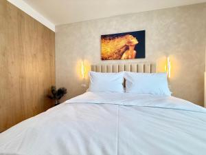 a bedroom with a white bed with a painting on the wall at FeWo No 407 Lebada Lake in Pantelimon