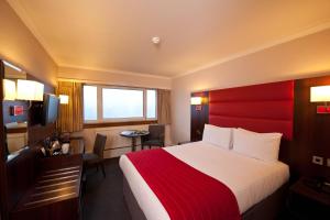 a hotel room with a large bed with a red headboard at Leonardo Inn Glasgow West End in Glasgow