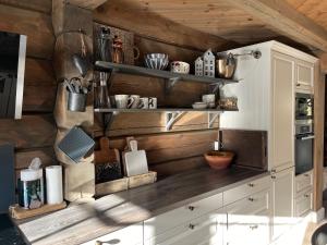 una cucina con armadietti bianchi e pareti in legno di Ornenipa Lodge - stor flott hytte med 6 sov og 2 bad a Gaustablikk