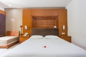 a bedroom with a large white bed and wooden walls at Sinar Bali Hotel in Legian