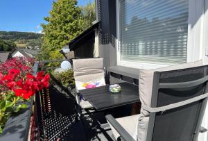 a porch with a table and chairs on a balcony at Upland-Flair Ferienwohnung BLUMENWIESE im Zentrum! in Willingen
