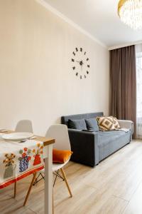 a living room with a couch and a table and a clock at Апартаменты возле Хан-Шатыра и Ботанического Сада in Astana