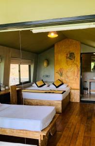 a room with two beds and a painting on the wall at Ele Camp Udawalawe in Udawalawe +63 photos