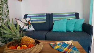 a blue couch with a bowl of fruit on a table at Tikaz Turkoiz T3 Manganao in Saint-François