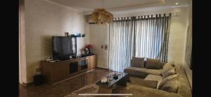 een woonkamer met een bank en een tv bij Maison Verde Madinaty in Banī Ghālib