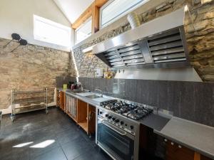 a large kitchen with a stove and a sink at Moderscheid Cottage with Spa in Amblève