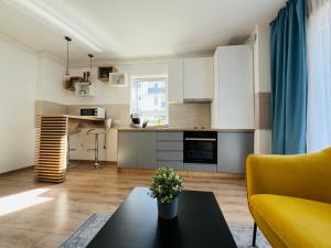 a kitchen and living room with a table and a yellow couch at Apartment Richy Brasov in Braşov