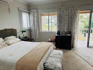 ダーバンにある6A on Redwood Guest House in Durban Northの大きなベッドと2つの窓がある寝室