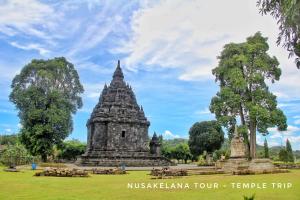 a temple in a park with trees and a cloudy sky at Gorga hostel in Yogyakarta