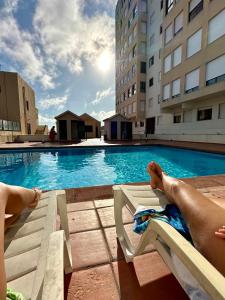 two people laying on lounge chairs next to a swimming pool at 3 balconies with sea view - restaurants below - personalized support - Ponta Delgada -DOMOSTAY AL in Ponta Delgada