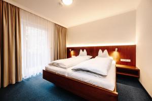 a bedroom with a large bed with white pillows at Hotel Reindl Suiten & Appartments in Bad Füssing +55 photos