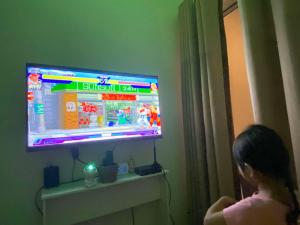 een jong meisje dat een videogame speelt op een televisie bij La Mari 1 bedroom at Prisma Residences in Manilla +6 foto's