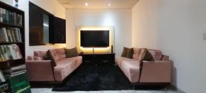 a living room with two couches and a flat screen tv at Casa há 300m do PARQUE DA CIDADE - COP 30 in Belém
