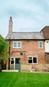 a brick house with two benches in front of it at Hazelbury Cottage in Wilton