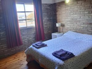 Un dormitorio con una cama con toallas azules. en El Cardal II, en Río Cuarto