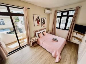 a bedroom with a pink bed and a large window at Sam & Chlo Studio & Appartment - Grand Baie - Mauritius in Grand-Baie