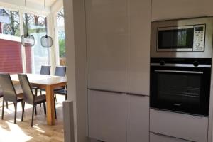 a kitchen with a table with chairs and a microwave at Dock 2 - tolles Ferienhaus für bis zu 6 Personen mit Kaminofen und Sauna - Haustiere herzlich willkommen in Nordhorn