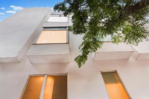 - un bâtiment blanc avec des fenêtres et un arbre dans l'établissement Super Townhouse Chhatarpur Near Metro Park, à Jāmb