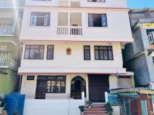 a white house with black doors and windows at Hotel Tashiling Stay in Pelling