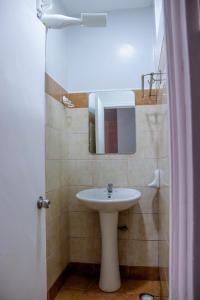 Un baño con un lavabo blanco y un espejo. en KiKha Nest, en Syokimau