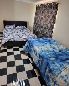 Un dormitorio con dos camas y suelo de cuadros. en Catalina Bay Beach Retreat - Dolphin Inn, en Hibberdene