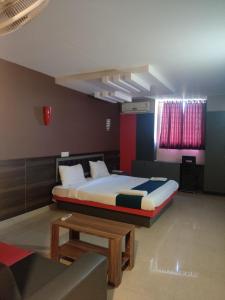 ein Schlafzimmer mit einem Bett, einem Tisch und einer Couch in der Unterkunft EMPIRE THE GRANDE SUITEs in Ernakulam