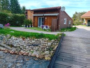 a cabin with a wooden walkway next to a body of water at ChaletBijoux in Gérardmer