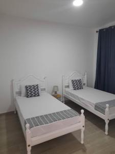 two white beds in a room with blue curtains at Tarrafal snuggle in Tarrafal