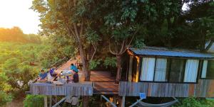 a group of people sitting at a table outside of a cabin at Napahong Treehouse forest camp in Ban Pa Ha