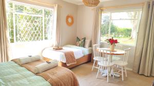 a bedroom with two beds and a table and a window at Willowlea Cottage in Underberg