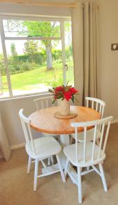 a table with white chairs and a vase with flowers at Willowlea Cottage in Underberg +15 photos