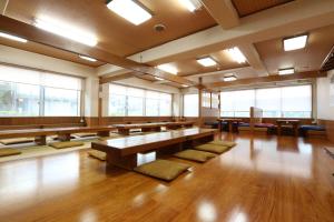 Habitación grande con bancos, mesas y ventanas. en Sun Flower City Hotel, en Setouchi