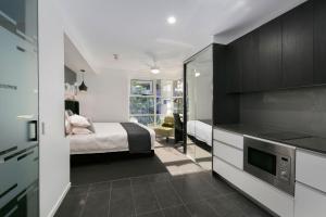 a small bedroom with a bed and a kitchen at Menso at Southbank in Brisbane