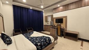 a bedroom with a bed and a kitchen and a television at The Maple Stays in Gurgaon