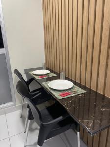a black table with two chairs and two plates on it at Los laureles Loft in Asuncion